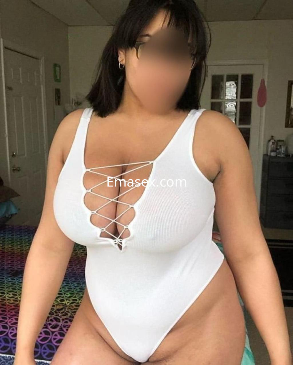 Escort en Zaragoza con bodysuit blanco ajustado, mostrando su figura en un ambiente interior.