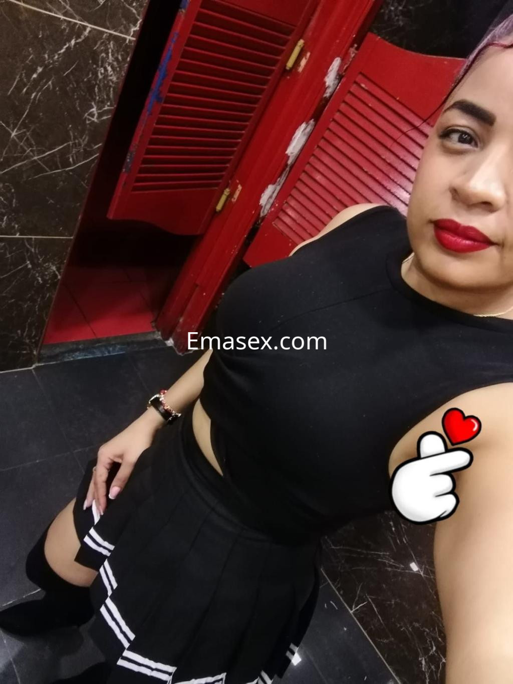 La puta muestra una blusa negra ajustada y una falda corta con detalles en blanco, en un entorno de Cádiz.