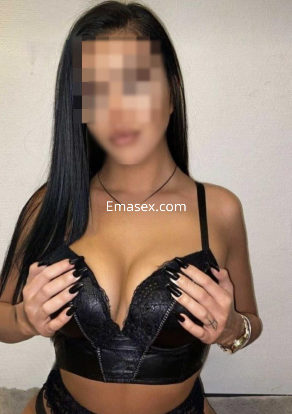 Escort en Cádiz con cabello largo y lacio, viste un sujetador negro ajustado y muestra una pose seductora.
