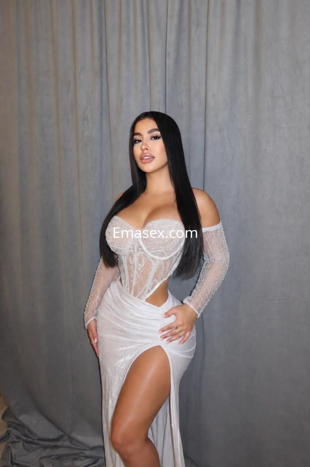 Puta posando con vestido blanco transparente y ajustado en Málaga, mostrando su figura y una pierna.