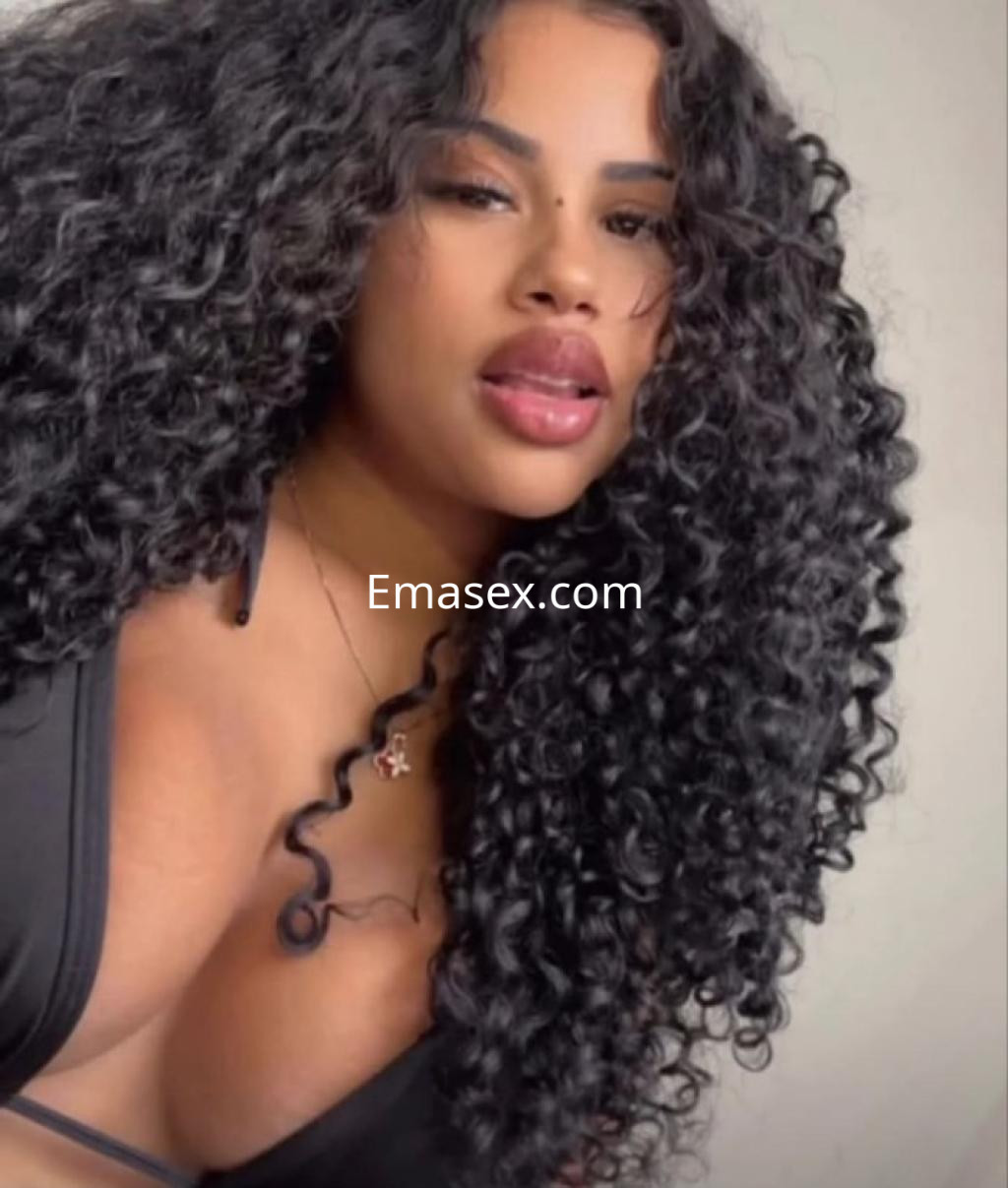 Escort de Girona con cabello rizado y oscuro, vistiendo un bikini negro que resalta su figura.