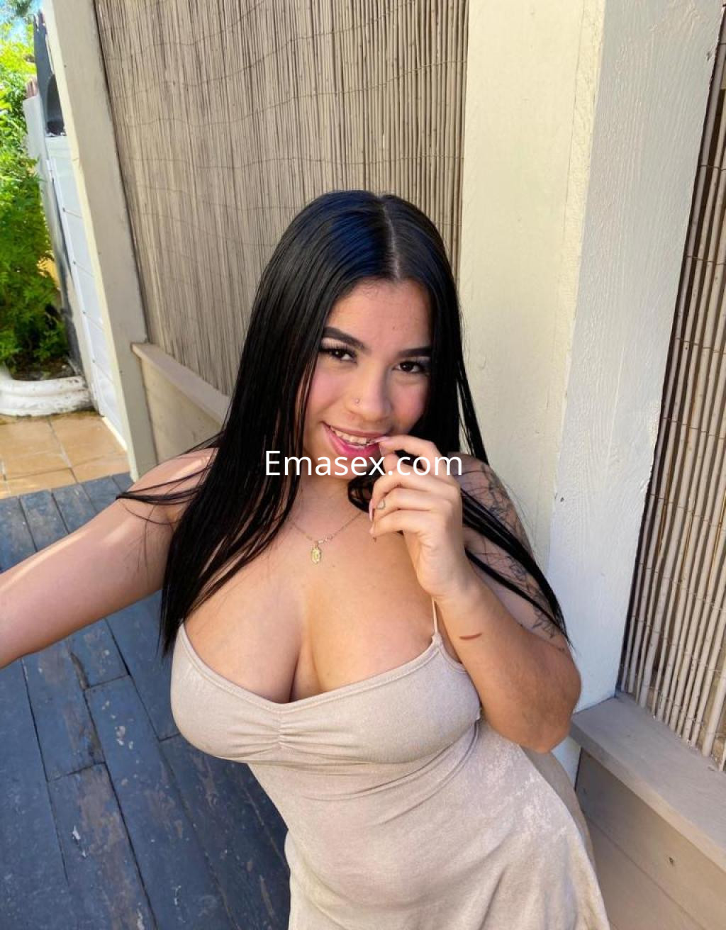 Escort en Las Palmas con cabello largo y oscuro, vistiendo un vestido claro, sonriendo y mostrando una pose coqueta.