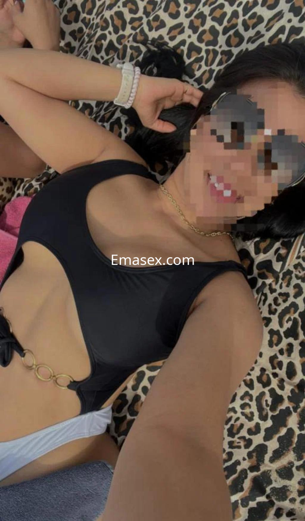 Escort en Las Palmas posando con un bañador negro, gafas de sol y cabello suelto sobre un fondo de estampado animal.