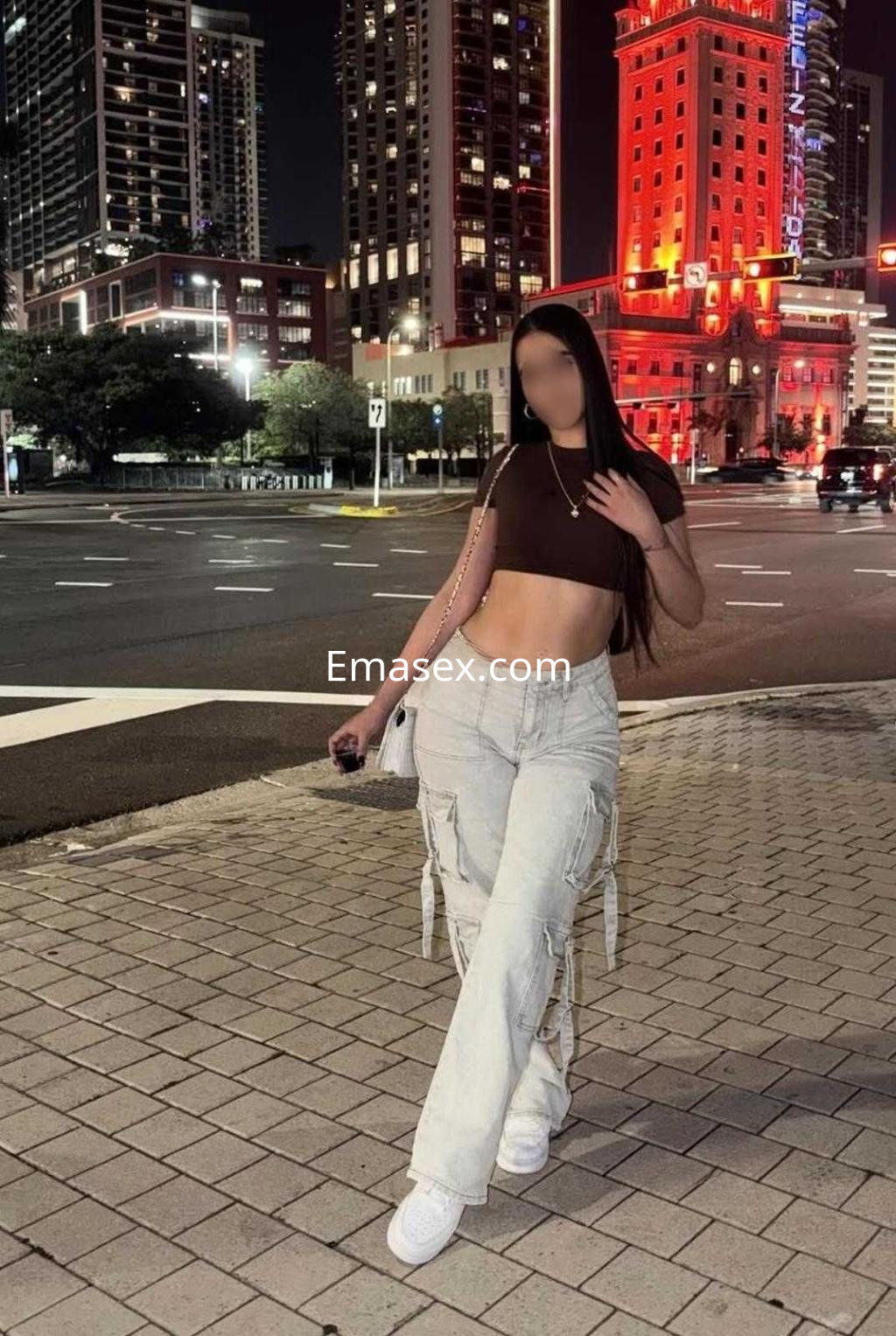 Escort de Albacete viste un top corto y pantalones anchos, caminando por una calle iluminada de noche.