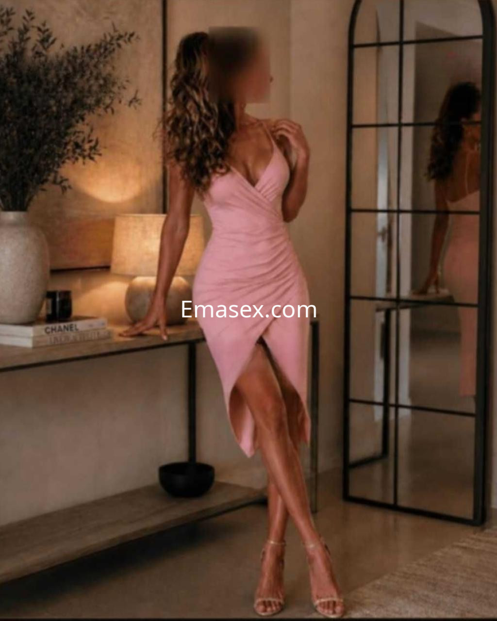 Puta en Valencia luciendo un vestido rosa ajustado con abertura lateral, posando en un entorno interior elegante.