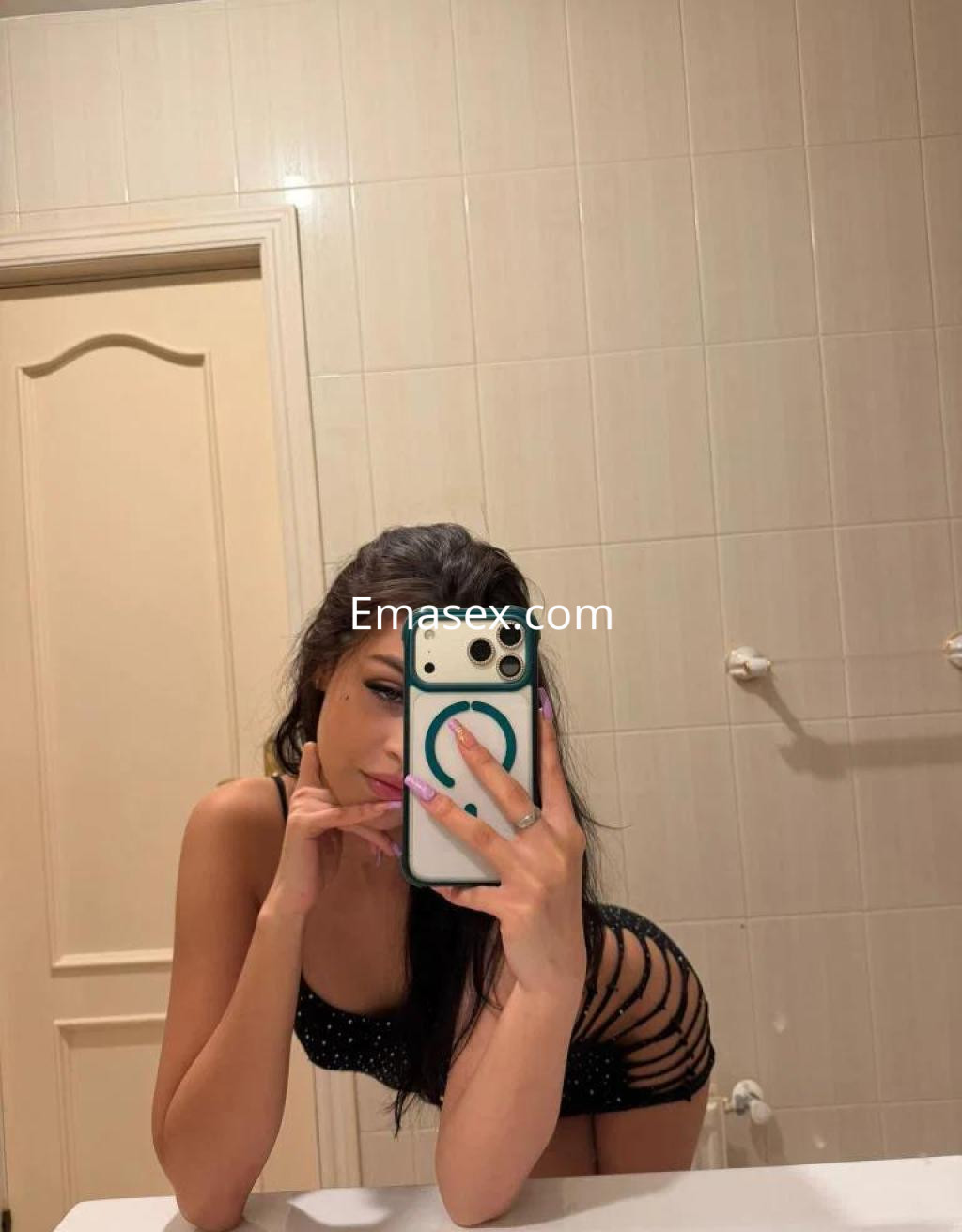 Escort en Madrid, posando frente al espejo con un conjunto negro de lencería y detalles de encaje.