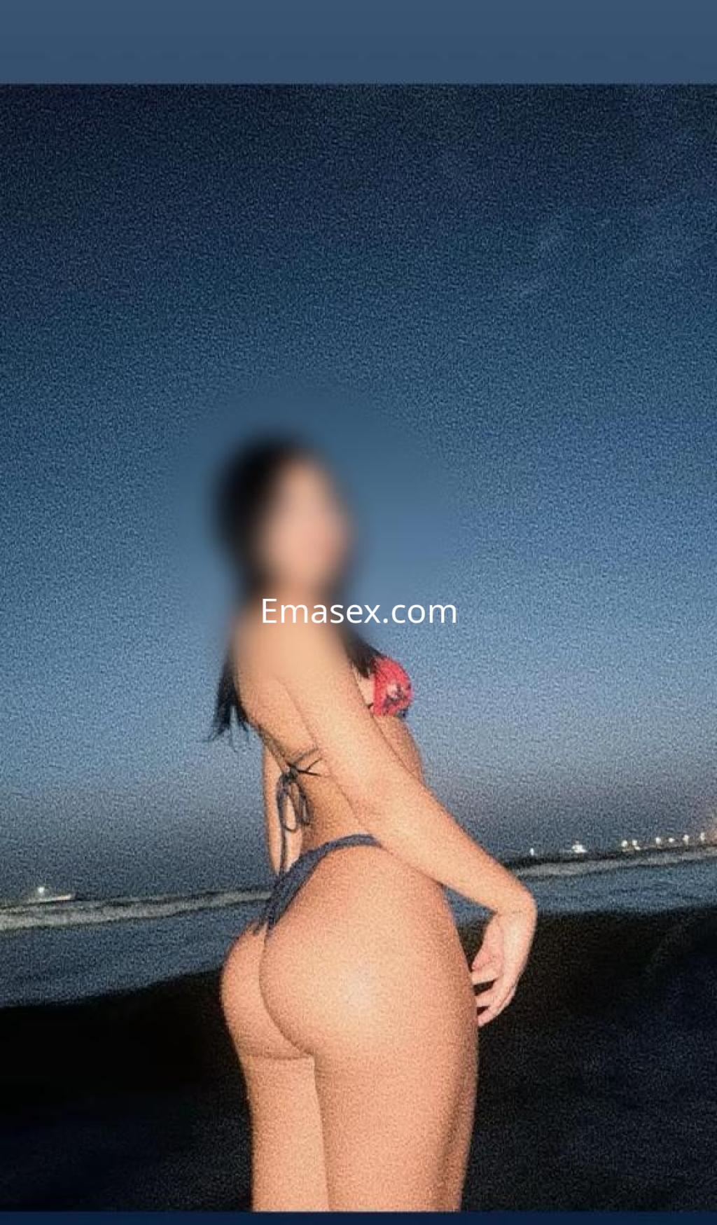 Escort de Madrid posando en la playa al atardecer, luciendo un bikini colorido y con el cabello largo.