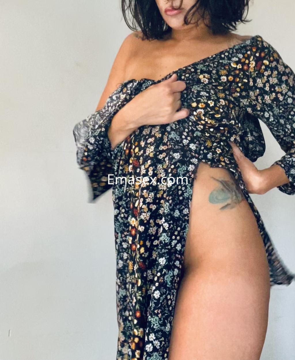 Escort en Irún con cabello oscuro y lacio, viste un vestido negro con flores que deja al descubierto parte del muslo.