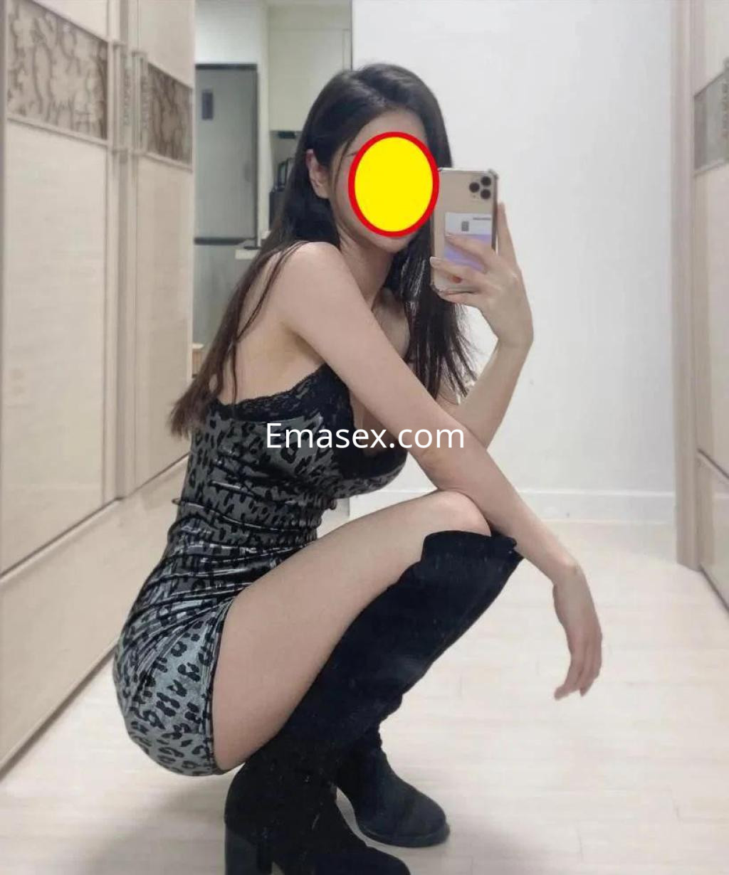 Escort en Barcelona con vestido ajustado de animal print, posando en un espejo y con botas altas.