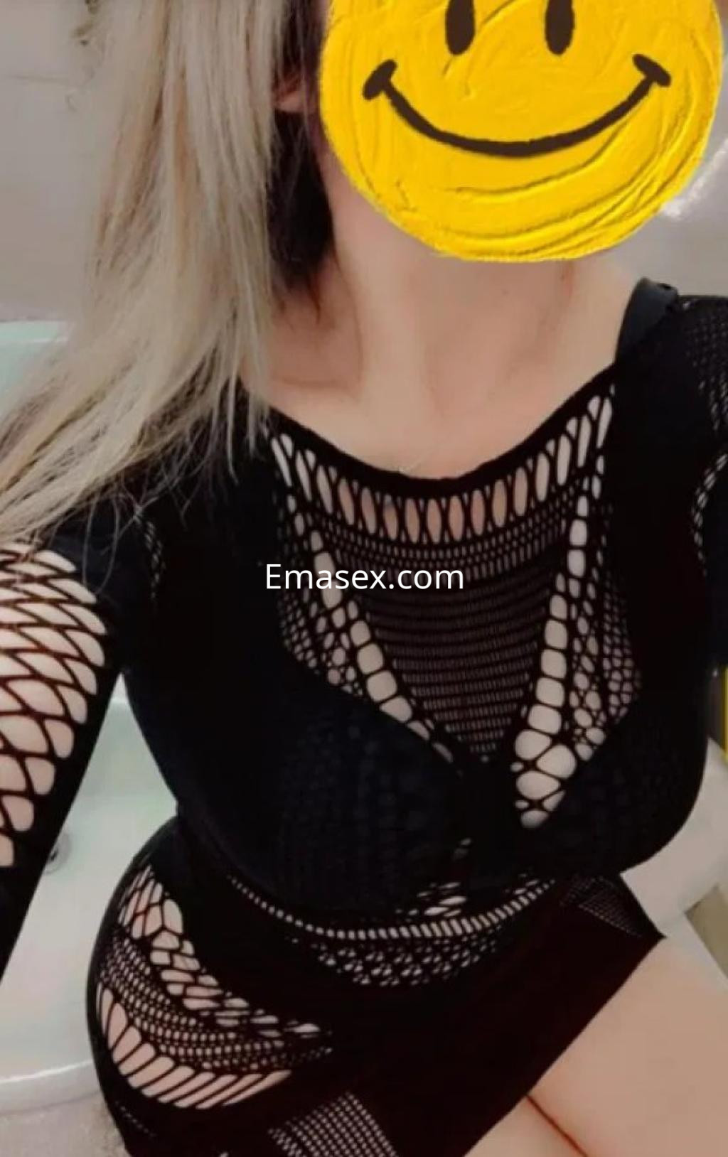 La puta luce un vestido negro de malla con detalles de red, posando de forma seductora en un entorno íntimo en Zamora.