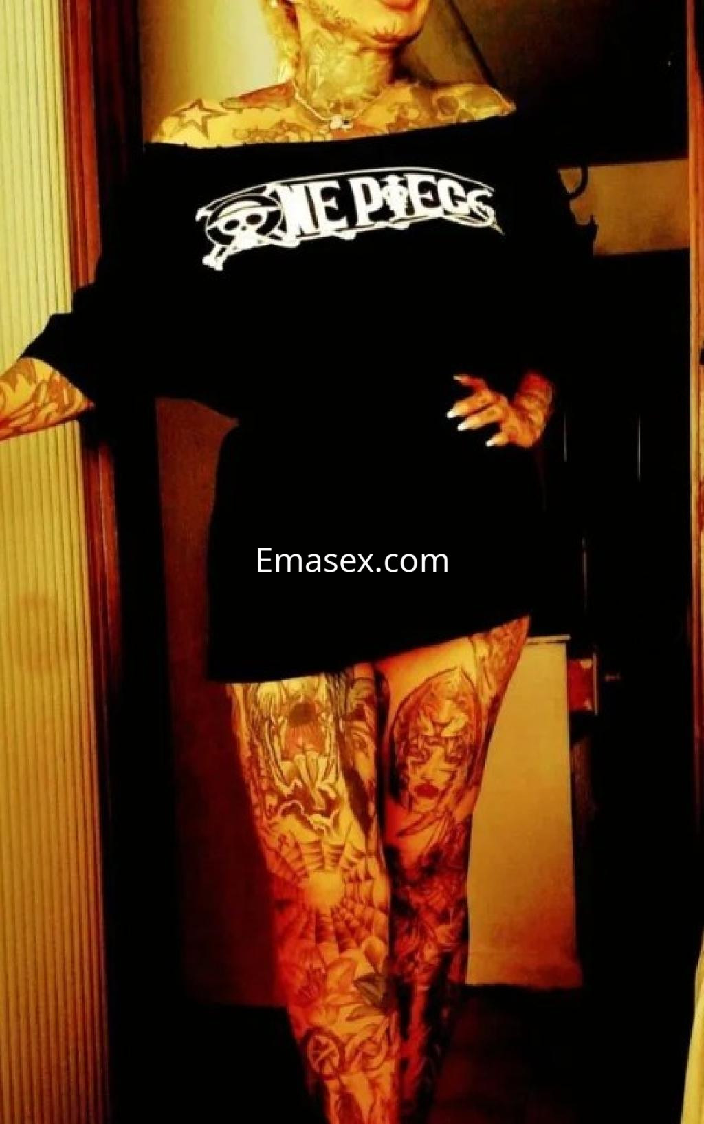 Escort en Ourense luciendo una camiseta negra oversized y exhibiendo tatuajes en brazos y piernas.