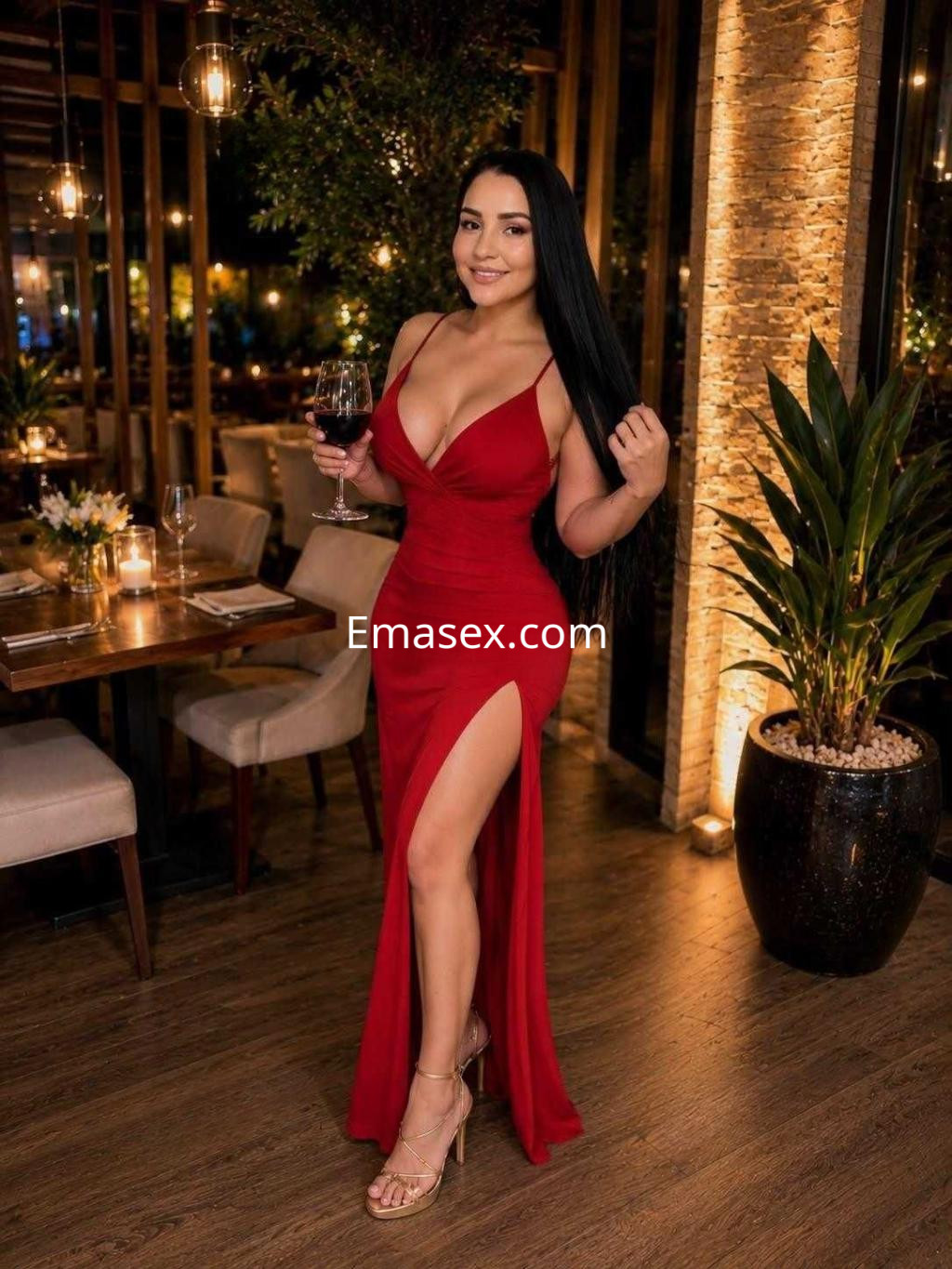 Escort en Barcelona con un vestido rojo ajustado y una abertura lateral, sosteniendo una copa de vino en un elegante restaurante.