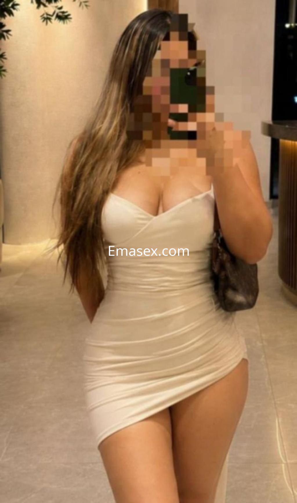 Escort en Castellón luciendo un vestido blanco ajustado y posando con una mano en la cadera.