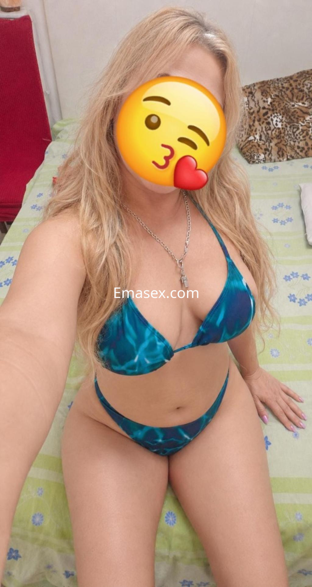 Escort en Logroño, posando en una cama con sábanas verdes, viste un bikini de color azul claro y tiene el cabello largo.