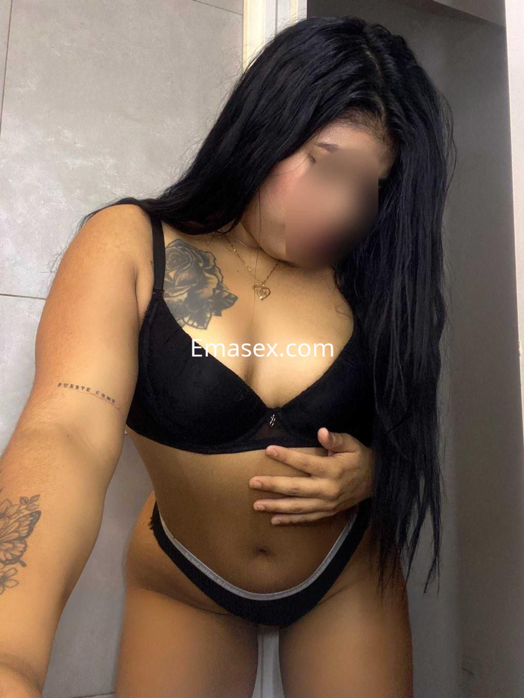 Puta en Valladolid se muestra de pie con un sujetador negro y una braguita, destacando su piel y tatuajes.