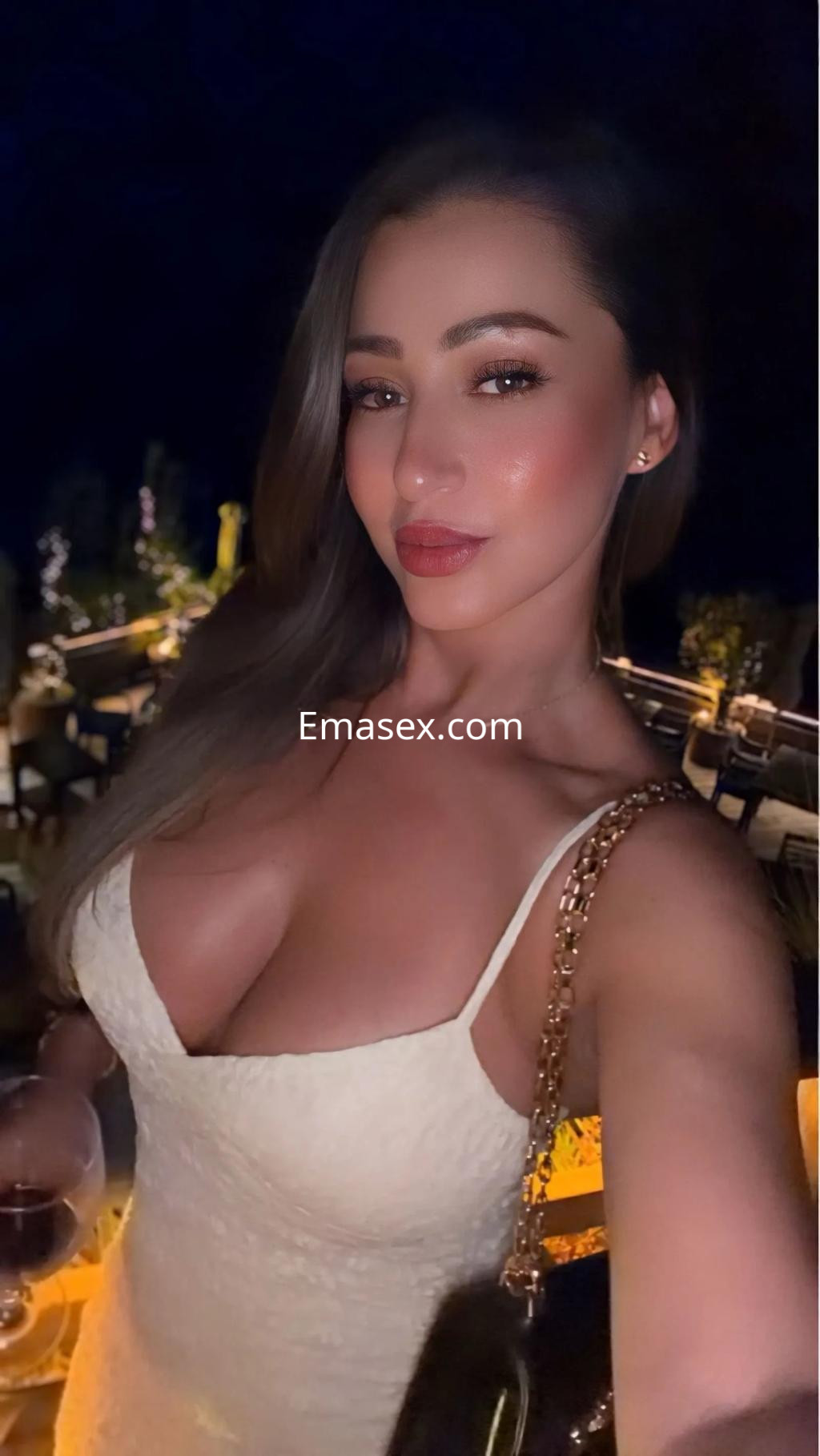 Puta con vestido blanco de escote, sosteniendo una copa, en un ambiente nocturno elegante en Zaragoza.