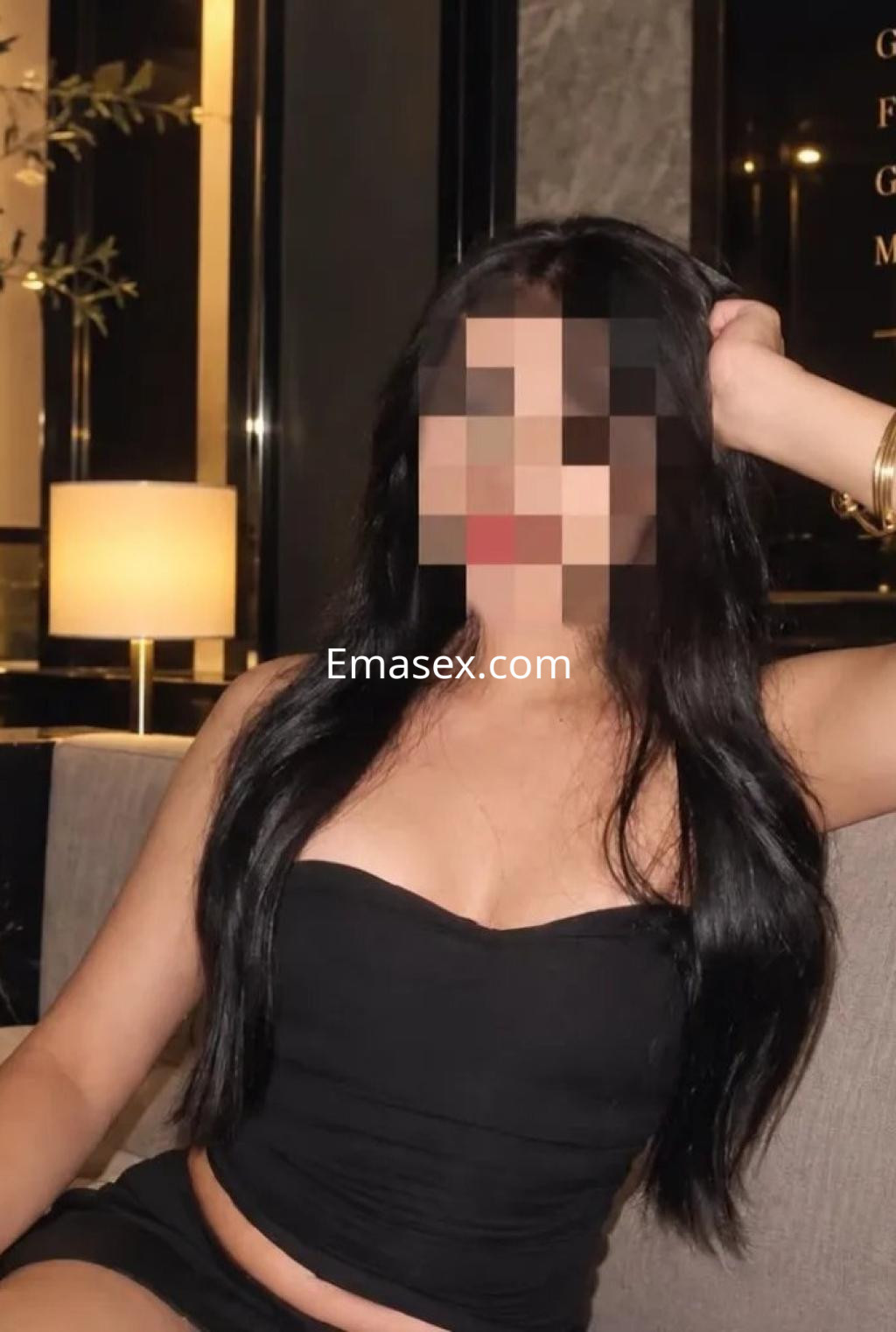 Escort en Valencia con cabello largo y lacio, luciendo un top negro y sentada en un ambiente elegante.