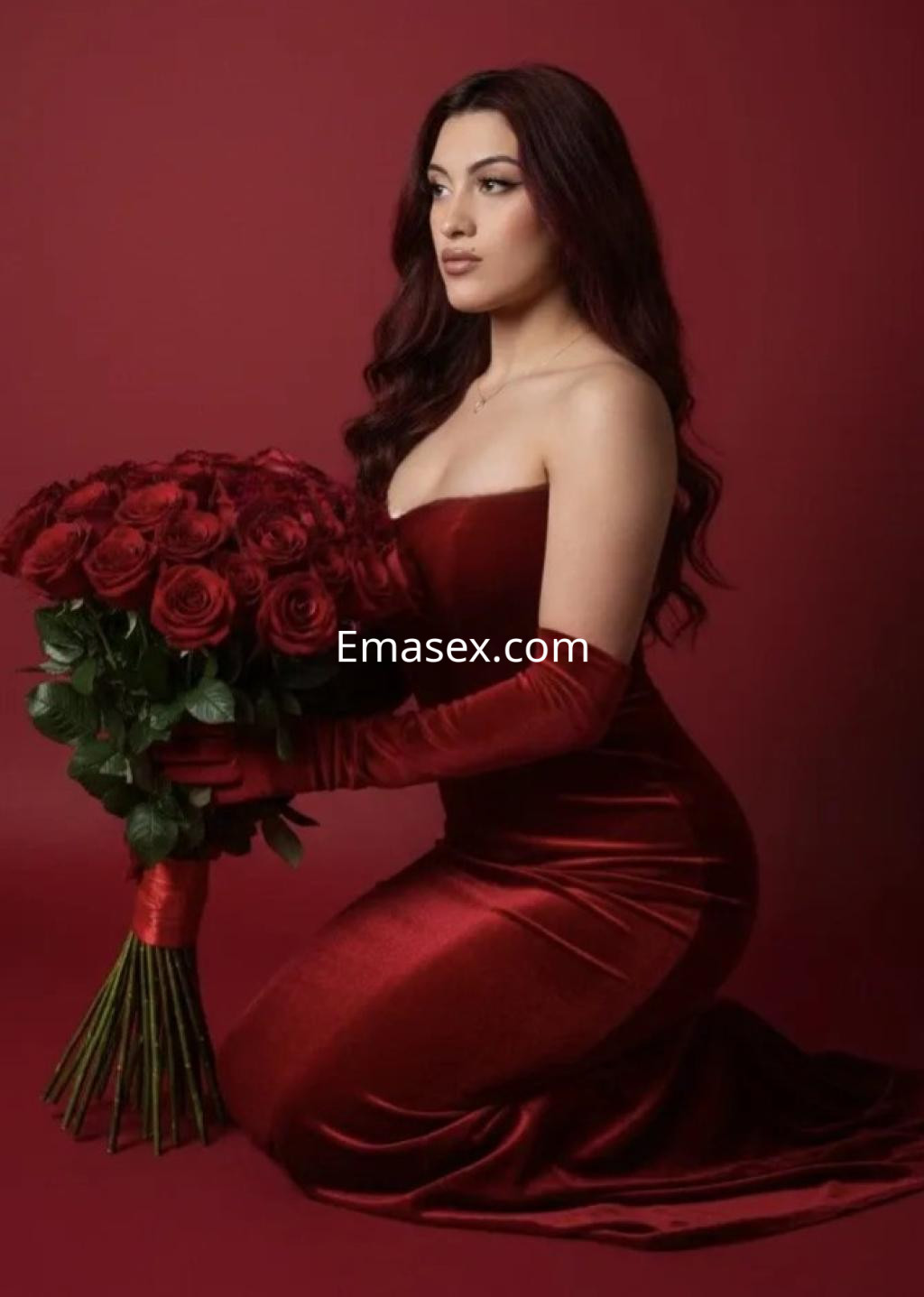 Puta en Palma de Mallorca, con cabello largo y oscuro, viste un vestido rojo y sostiene un ramo de rosas.