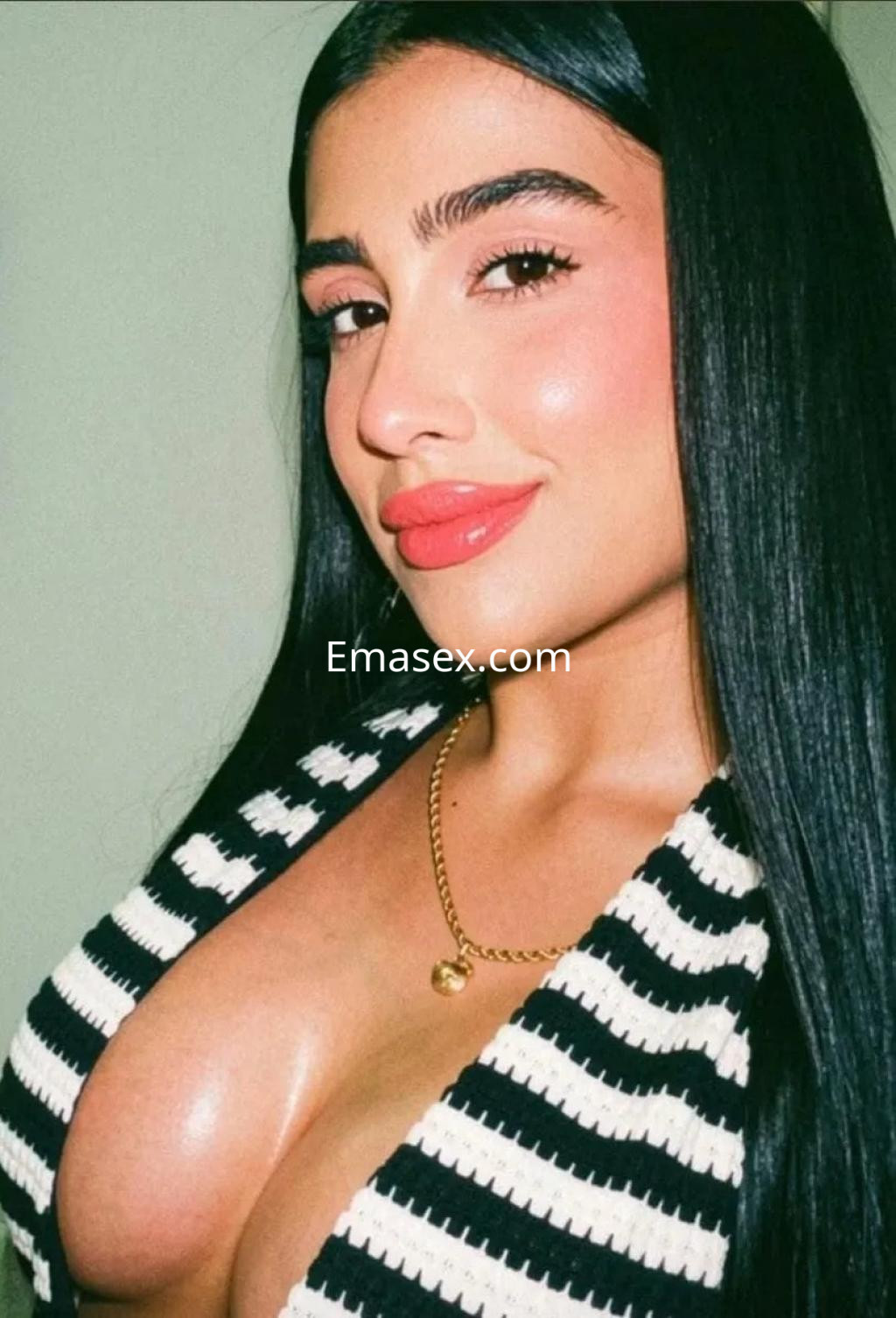 Escort en Toledo con cabello largo y lacio, luciendo un top a rayas y collar dorado, sonriendo a la cámara.