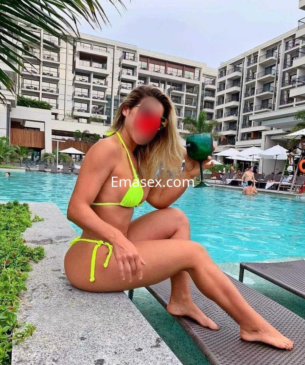 Puta posando en un bikini amarillo neón junto a una piscina en Pontevedra, sosteniendo una bebida.