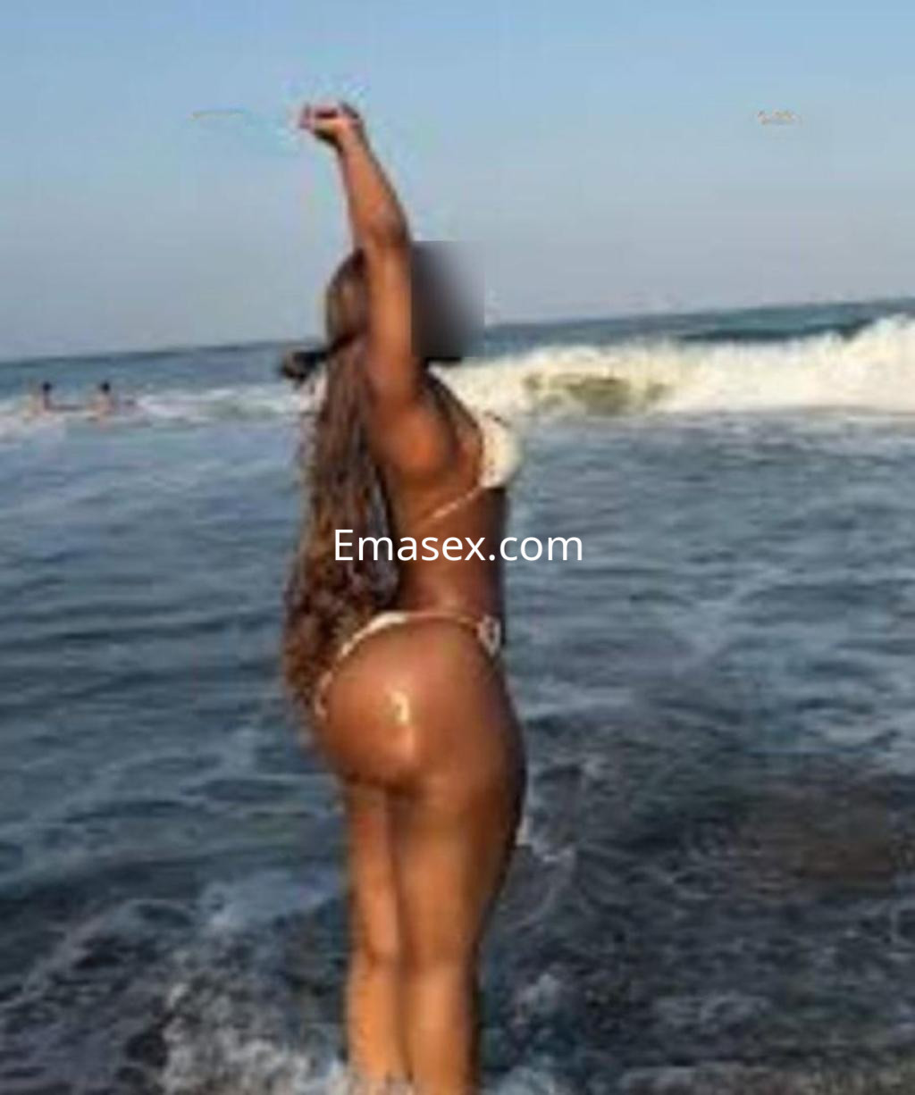 Escort posando en la orilla del mar en Almería, vistiendo un bikini y mostrando su cabello largo y ondulado.