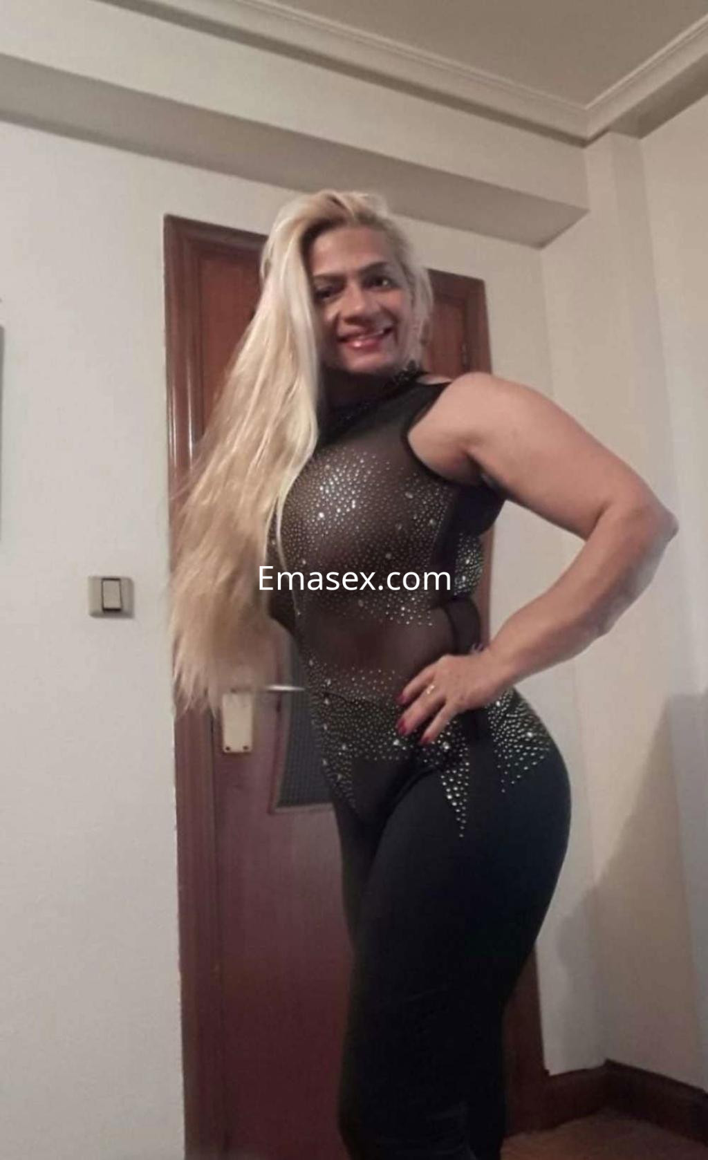 Escort en Valladolid con cabello largo y rubio, vistiendo un traje ajustado con detalles brillantes.