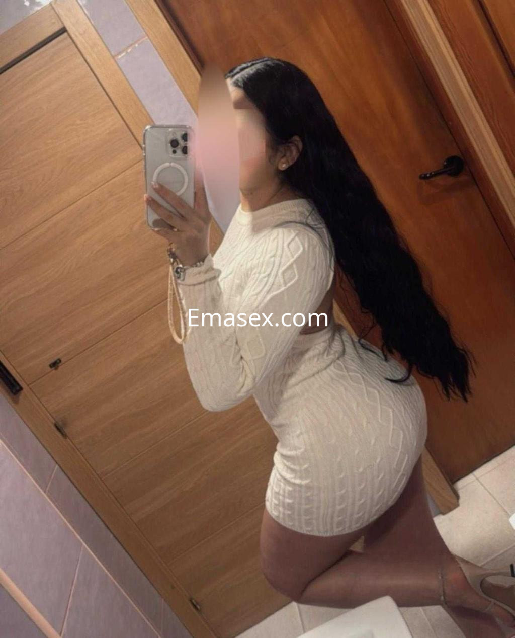 Puta posando en un vestido blanco ajustado en un baño, con el cabello largo y ondulado en Madrid.