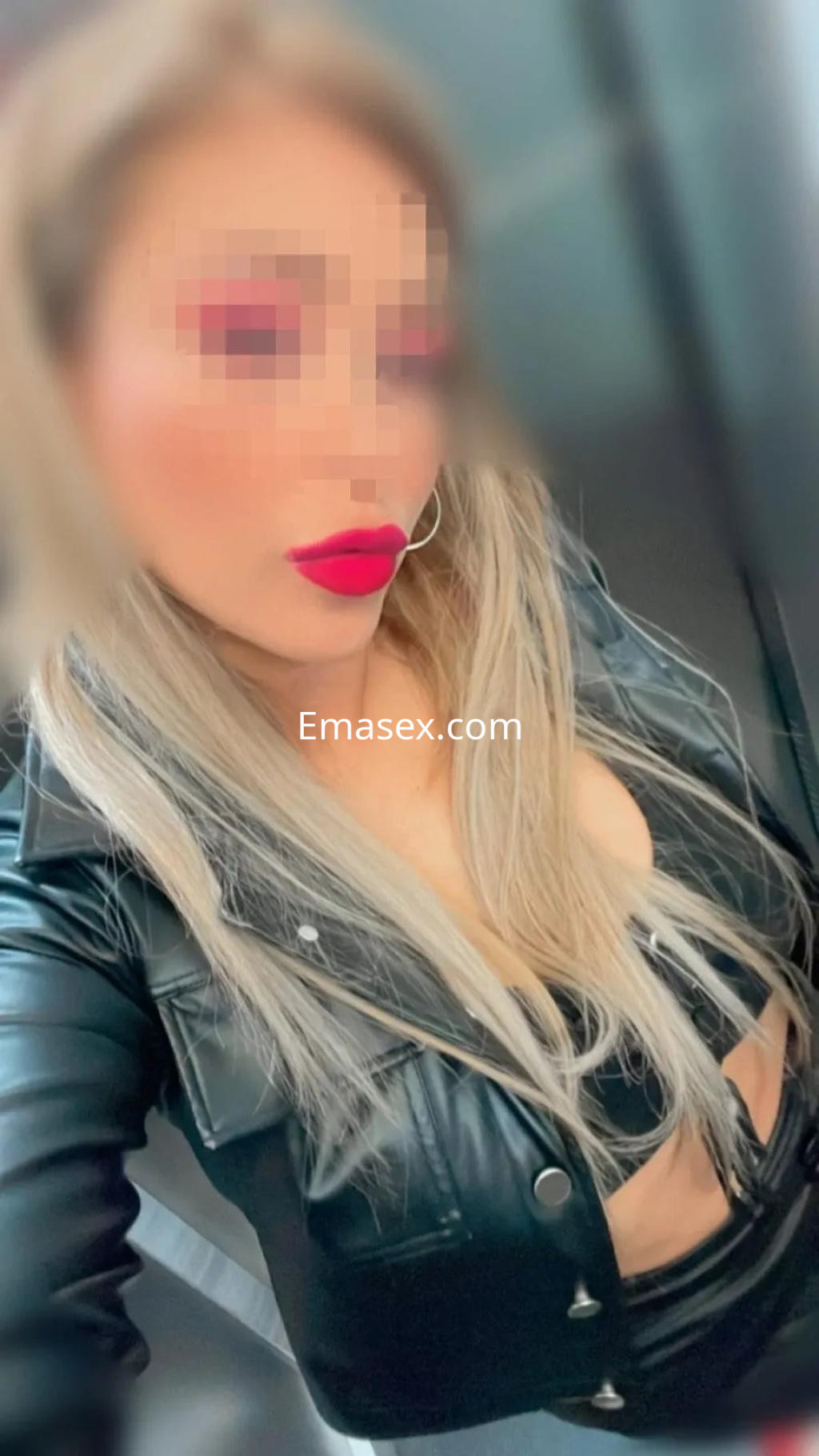 Escort en Madrid con cabello rubio largo, maquillaje llamativo y atuendo de cuero negro ajustado.