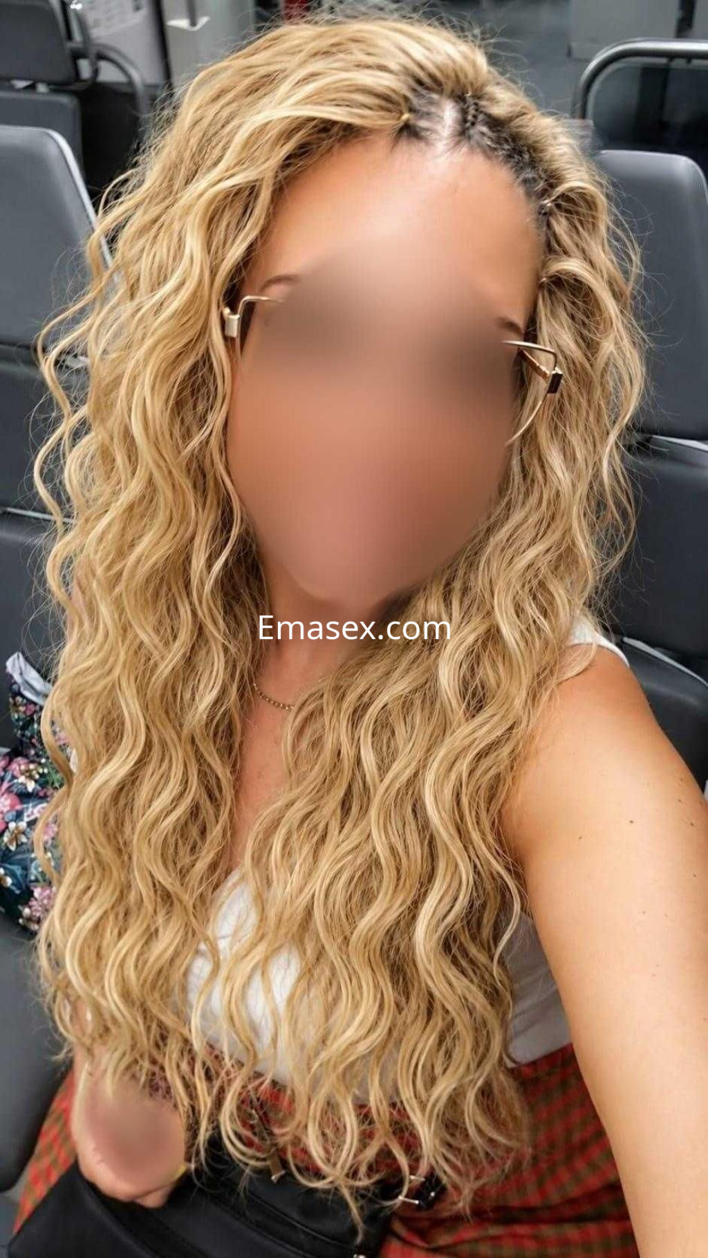 Puta con cabello rizado y rubio, lleva una blusa blanca y está sentada en un transporte público en Toledo.