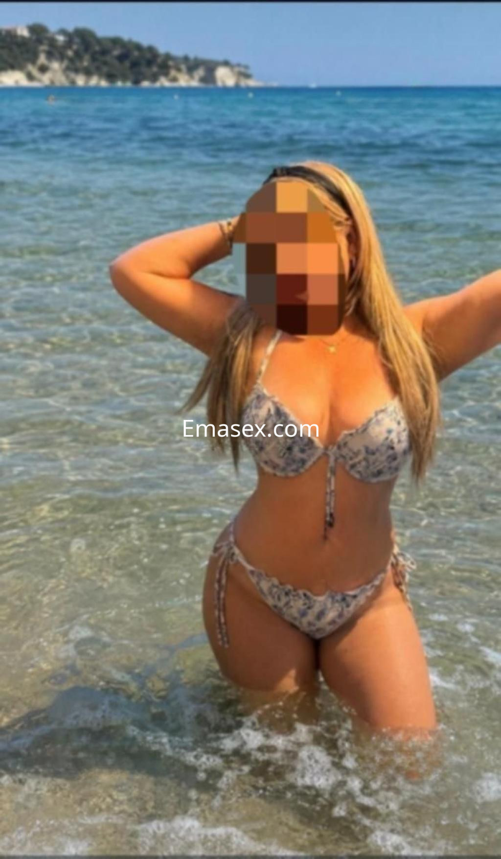 Puta en Toledo, posando en el agua con un bikini estampado, cabello largo y lacio, disfrutando del sol.