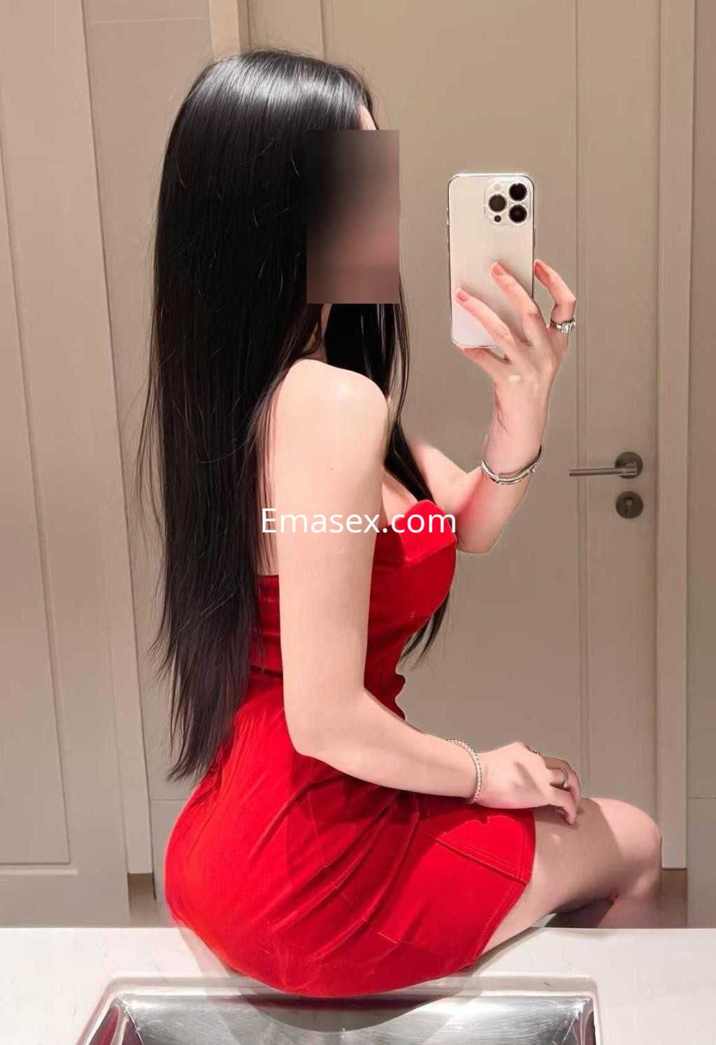 Puta con vestido rojo ajustado y cabello largo, posando frente al espejo en un baño en Madrid.