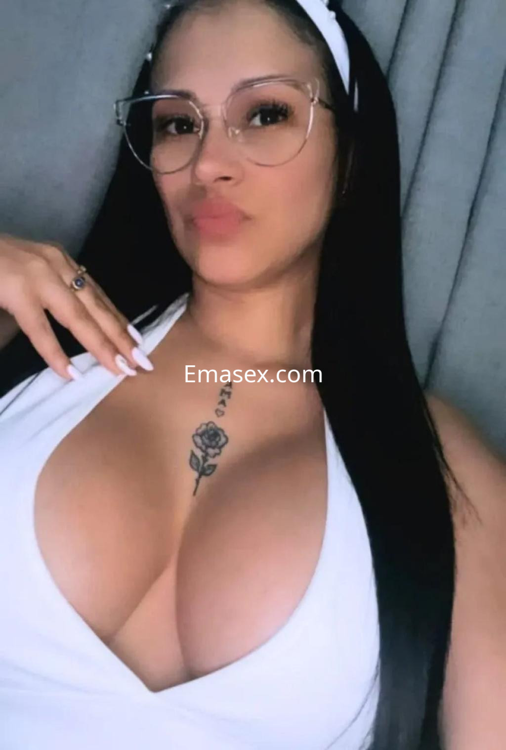 Escort en Palma de Mallorca con cabello largo y lacio, usando un vestido blanco y gafas, posando con una sonrisa.