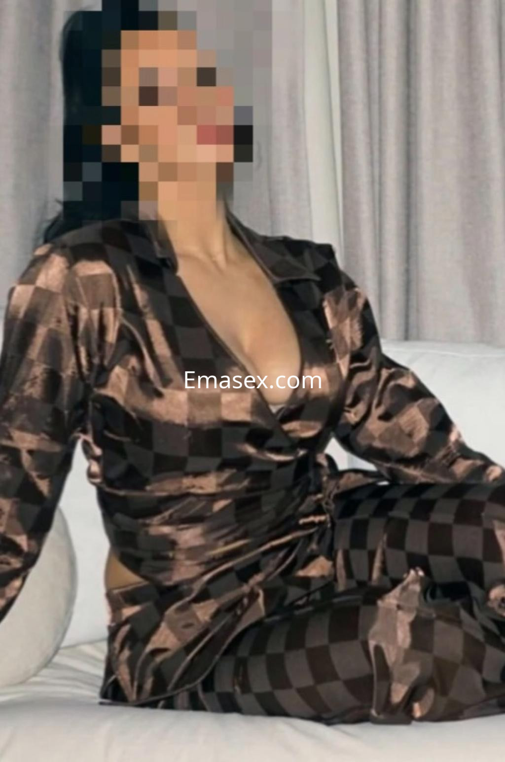 Escort en Donosti con un conjunto de pijama de cuadros marrones, posando de manera relajada en un sofá.