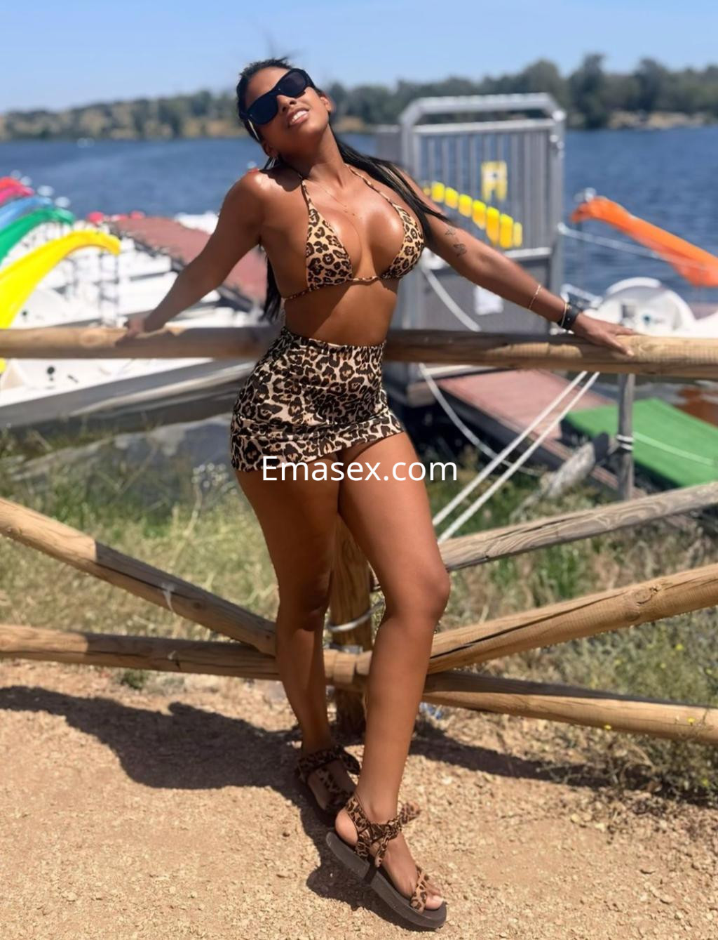 La escort en Logroño posa junto al agua, luciendo un bikini de leopardo y una minifalda a juego.