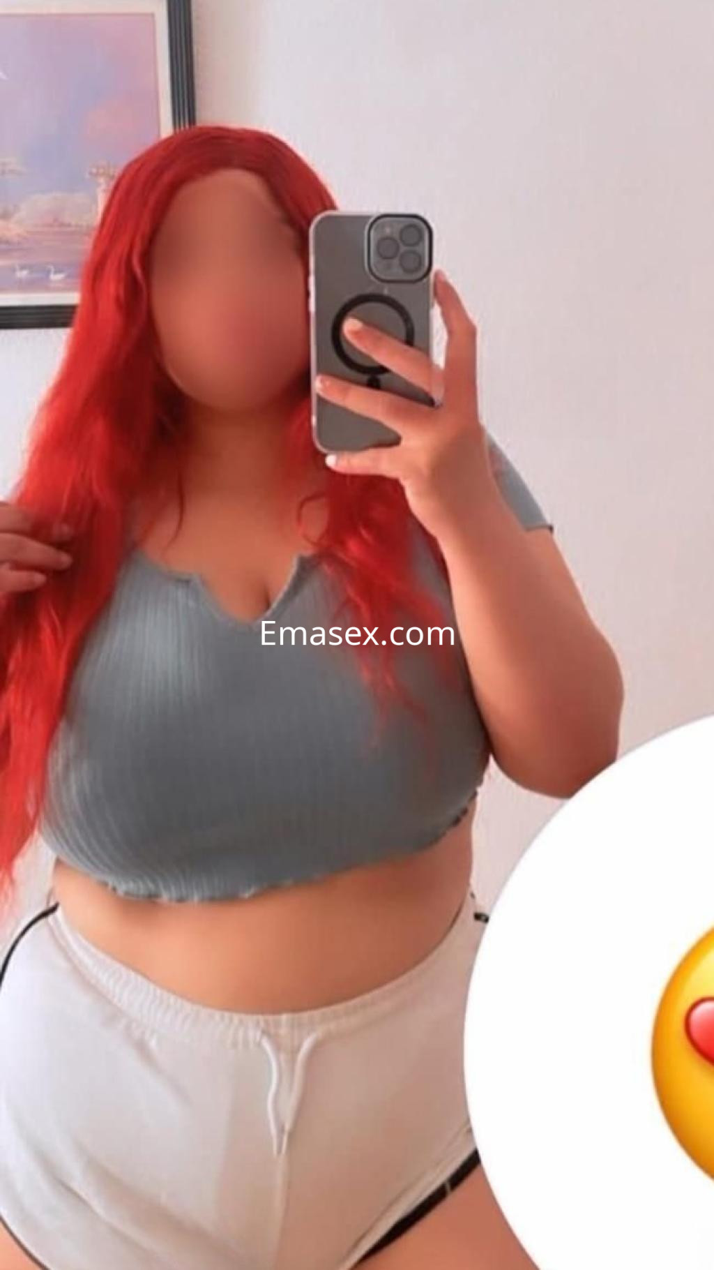 La puta en Barcelona se muestra con un top gris y pantalones cortos blancos, luciendo cabello rojo.