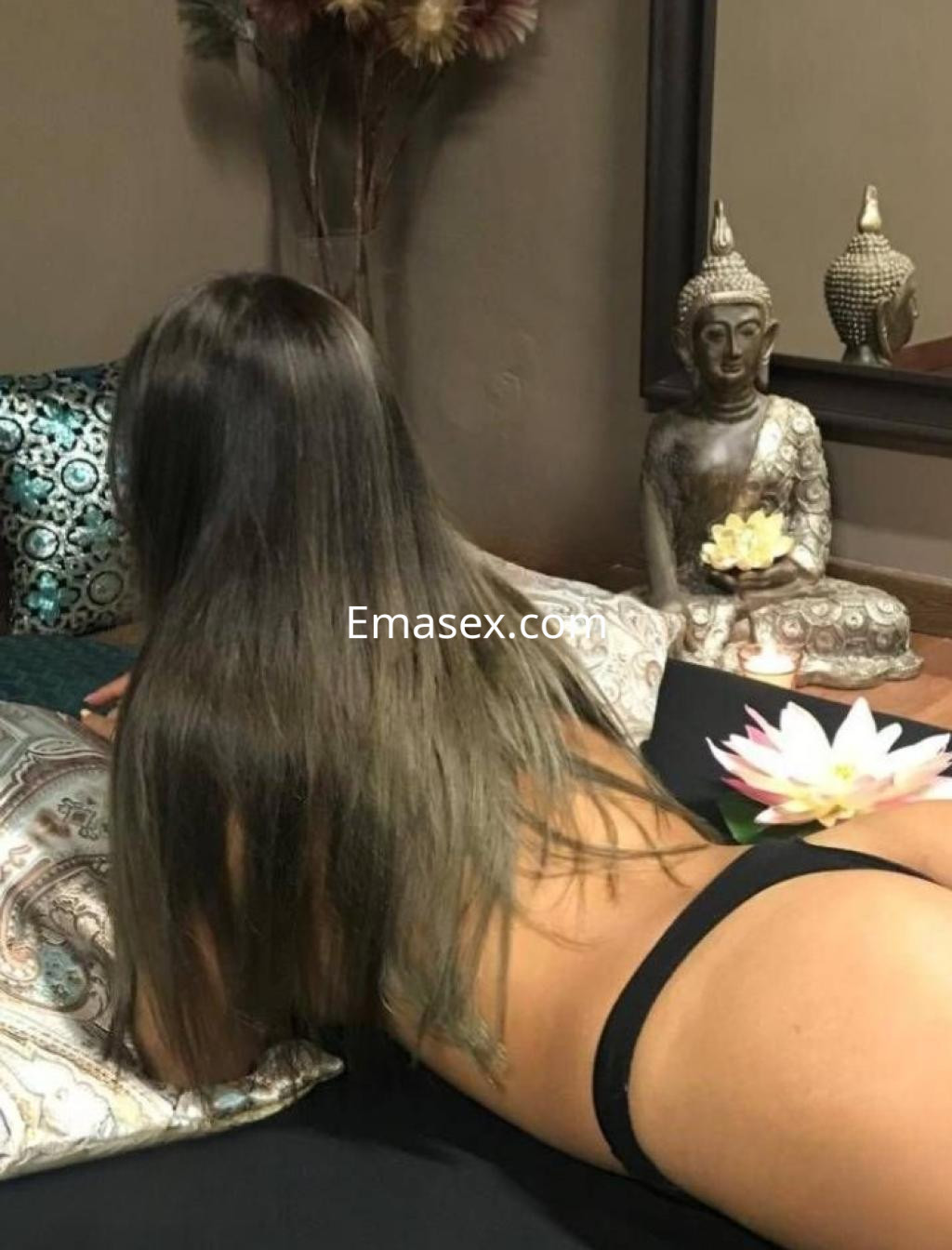Escort en Barcelona recostada sobre un sofá, luciendo lencería negra y con el cabello largo y lacio.