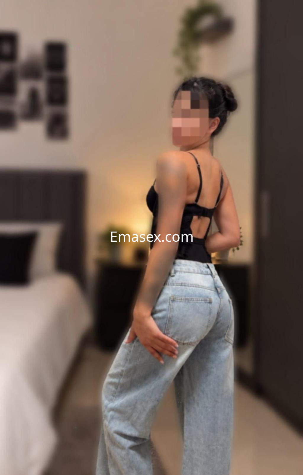 Puta de cabello oscuro y piel clara, vistiendo un top negro y pantalones anchos, posando en un dormitorio en Murcia.