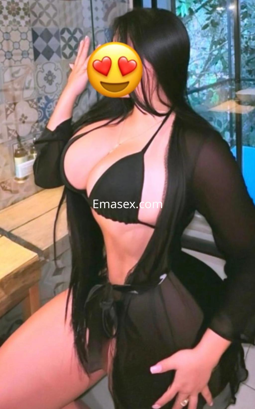 Escort en Ourense posa con un bikini negro y una bata transparente, mostrando una figura curvilínea.