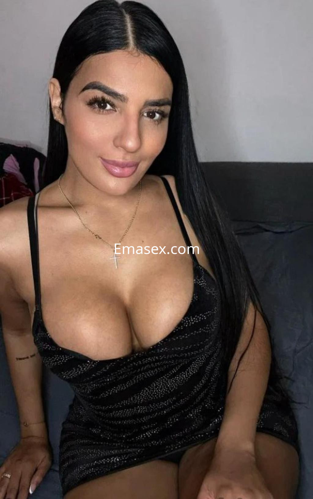 Escort en Valladolid sonriendo con un vestido negro ajustado y tirantes finos, con cabello largo y lacio.