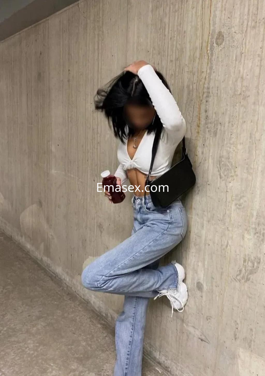 Puta en Coruña, apoyada en la pared, viste un top blanco, jeans claros y sostiene una botella, luciendo casual.