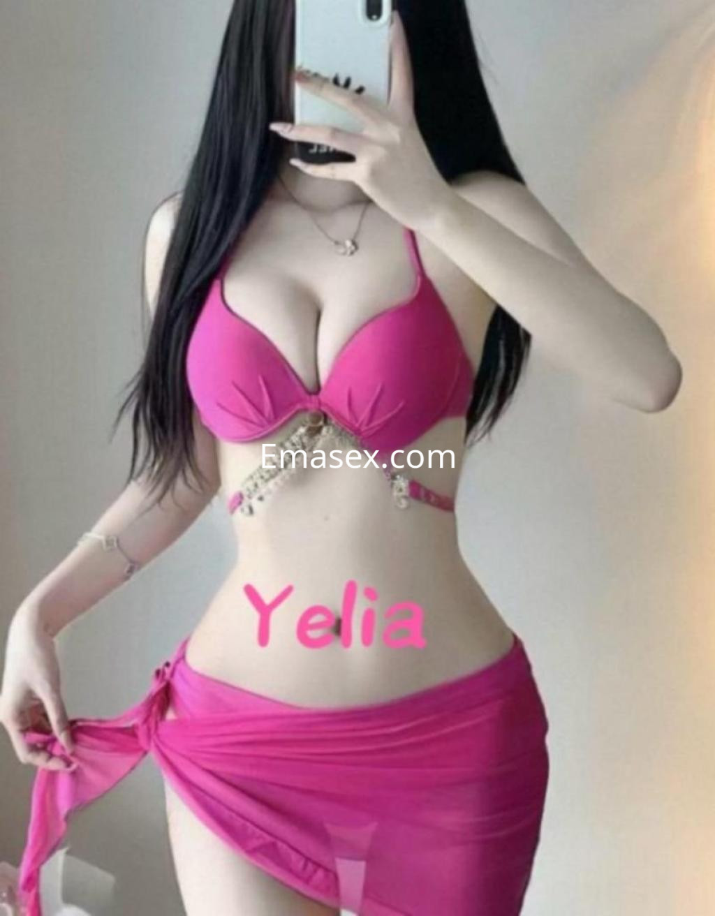 Escort en Tenerife luciendo un bikini rosa y una falda transparente, con cabello largo y oscuro.