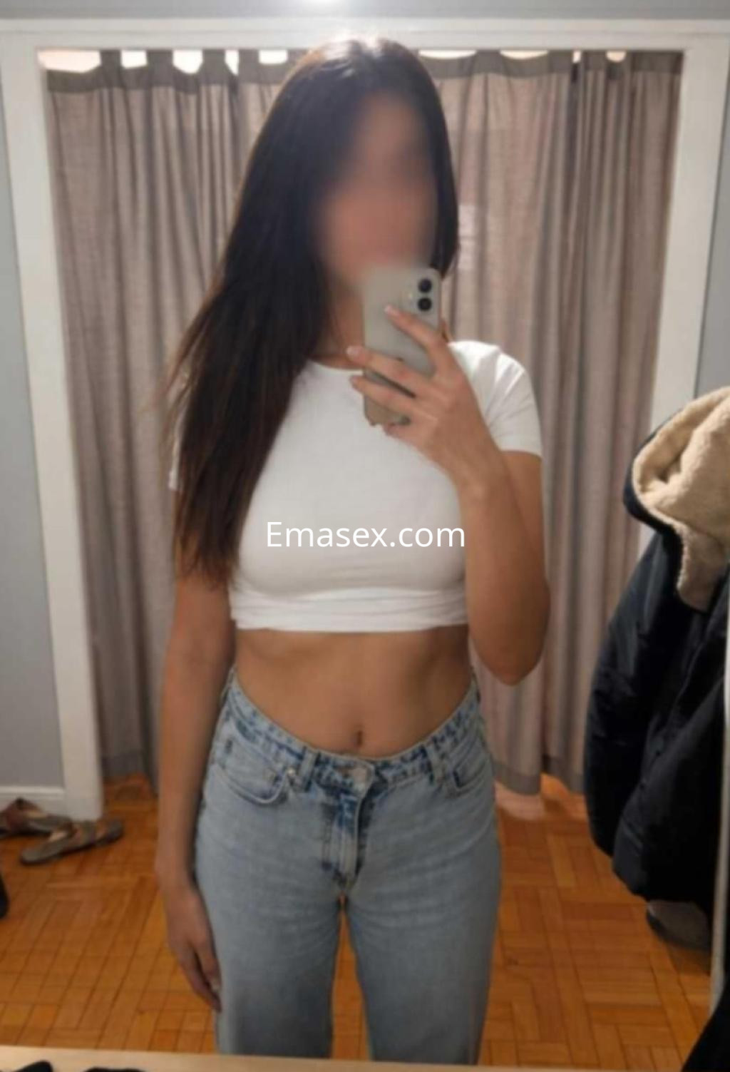 Puta en Vigo con cabello largo y lacio, vistiendo una camiseta blanca corta y jeans, posando frente a un espejo.