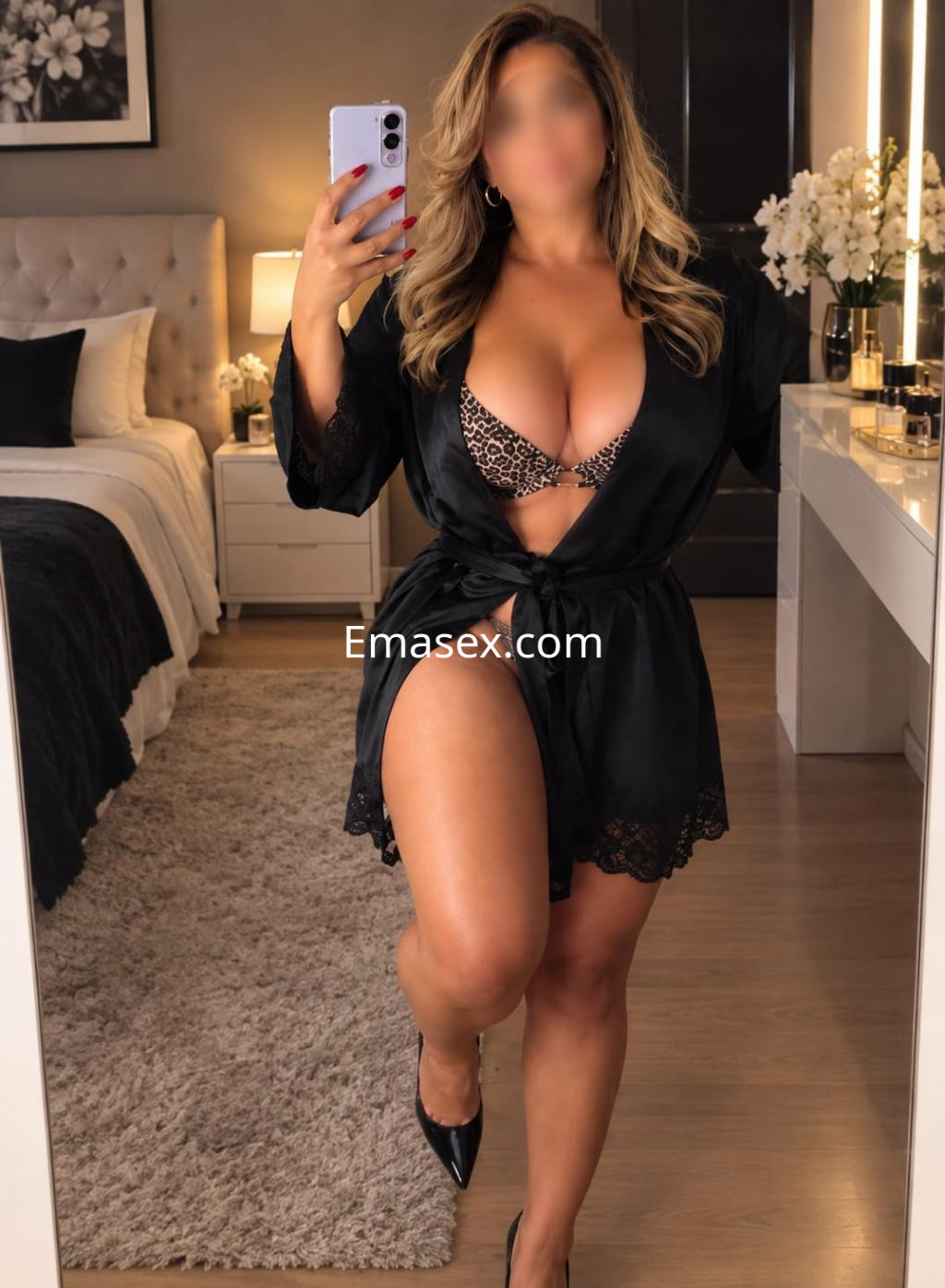 Escort en Valladolid, frente a un espejo, vistiendo un kimono negro y sujetador de estampado animal, con cabello suelto.