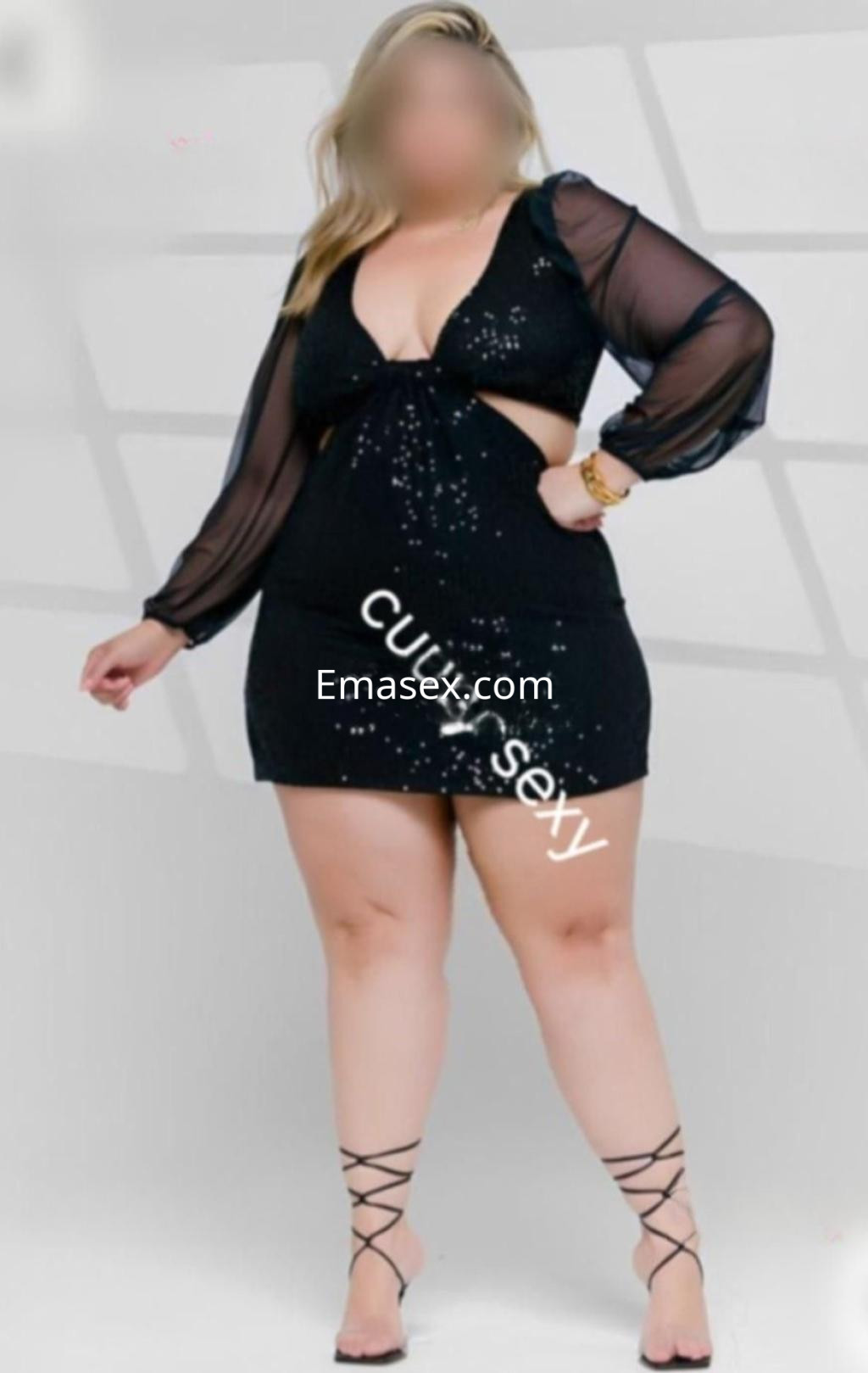 Puta en Madrid luciendo un vestido negro con transparencias y detalles brillantes, con sandalias atadas al tobillo.