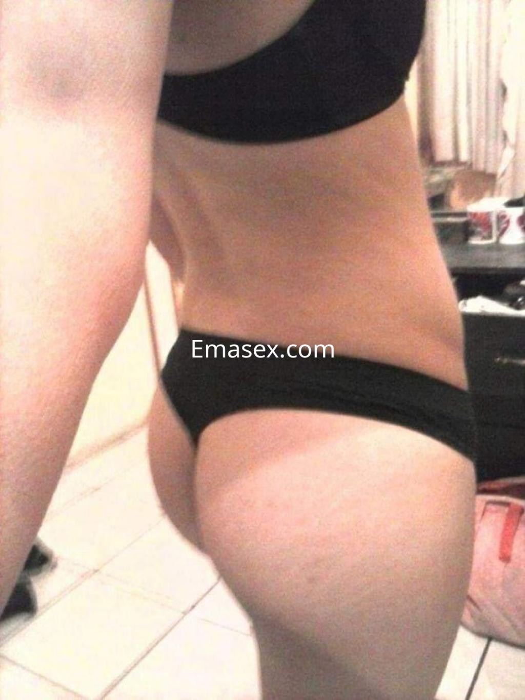 Puta en Salamanca posa de perfil luciendo lencería negra, destacando su figura esbelta y piel bronceada.