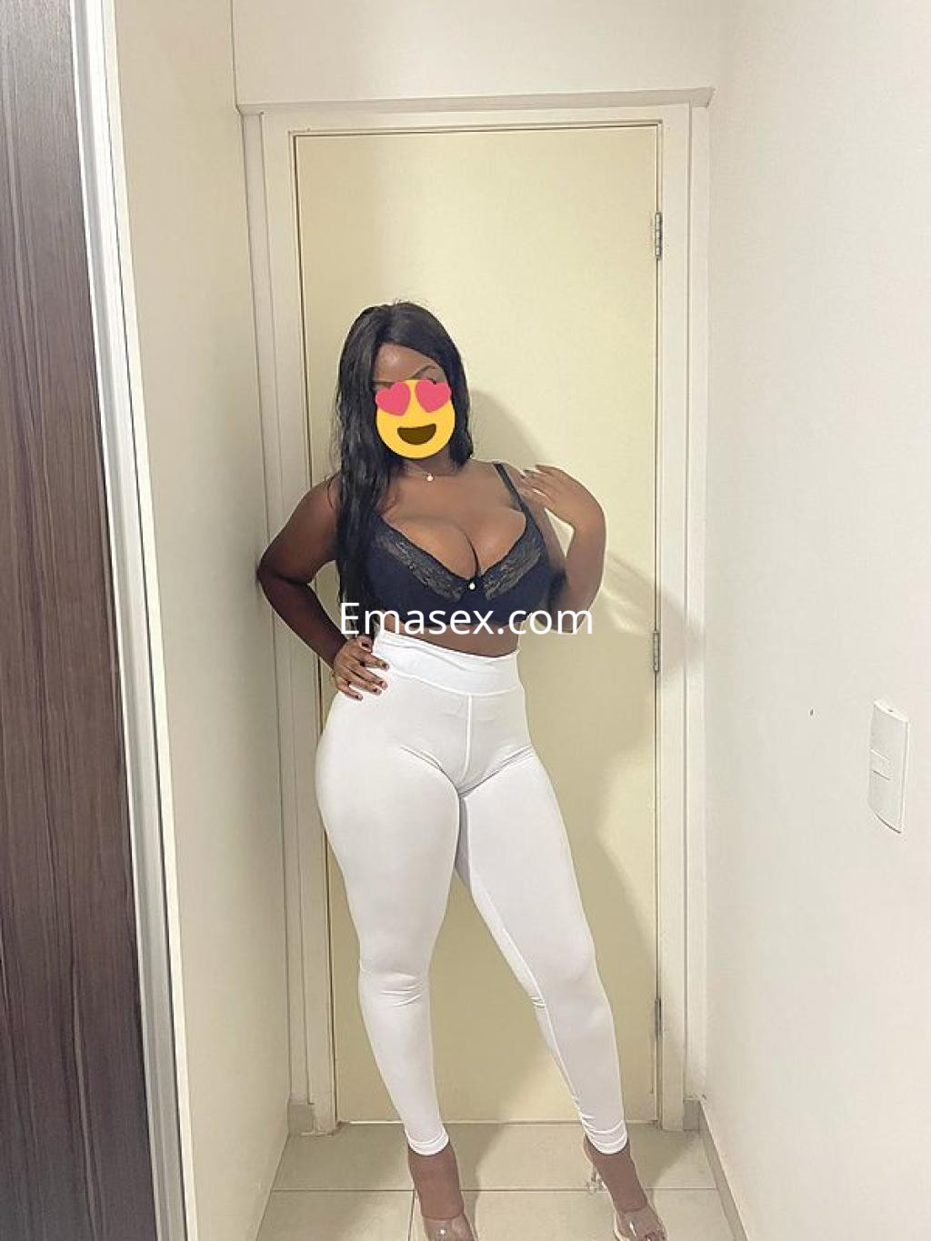 Escort en Salamanca con cabello largo y lacio, vistiendo un top negro y leggins blancos, posando en un interior.