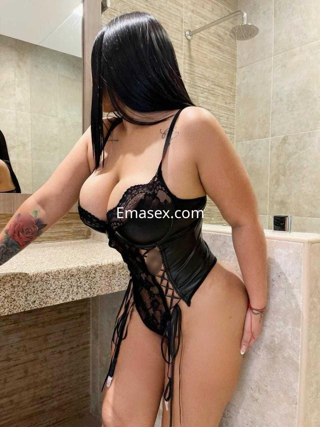 Puta en Madrid posando en un entorno de baño, vistiendo un conjunto de lencería negra con detalles de encaje.