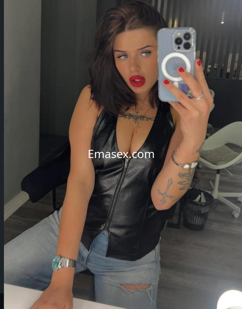 Escort en Barcelona con cabello oscuro y ondulado, vistiendo un top de cuero y jeans rotos, posando frente a un espejo.