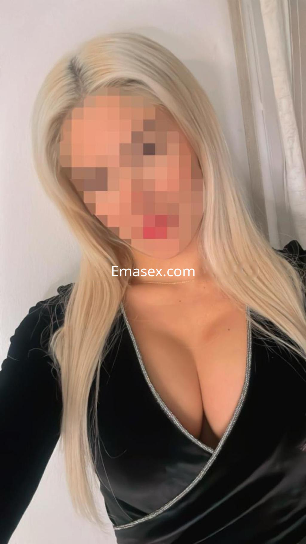 Escort en Girona con cabello rubio largo, vistiendo un vestido negro ajustado con escote pronunciado.