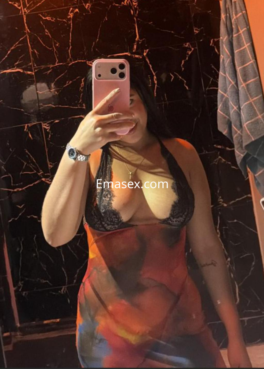 Escort en Donosti, con cabello largo y oscuro, viste un vestido ajustado con detalles de encaje, sonriendo mientras se toma un selfie.